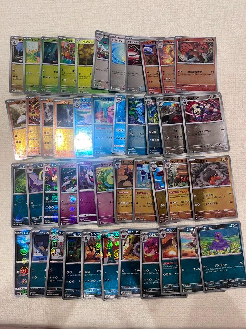Photograph of Pokémon trading cards spread on a light surface showing multiple holo and mirror cards.