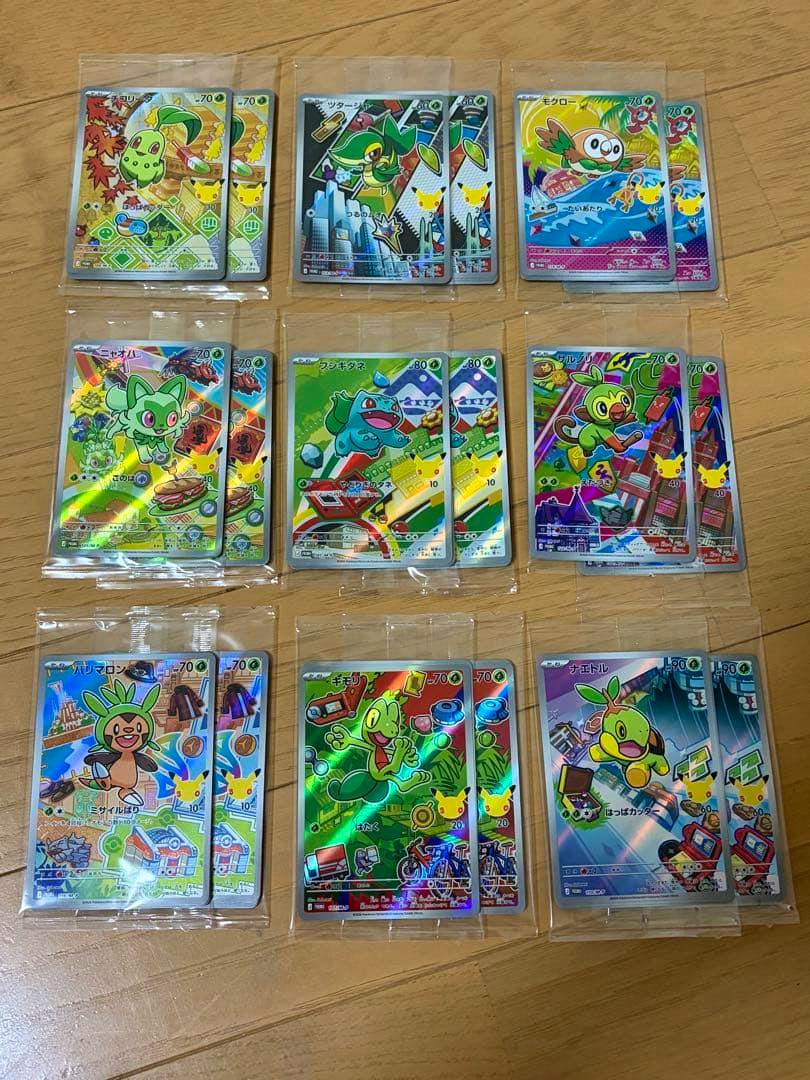 Multiple sealed Pokémon trading cards (30th anniversary starter promo AR cards) arranged in rows on a wooden floor.