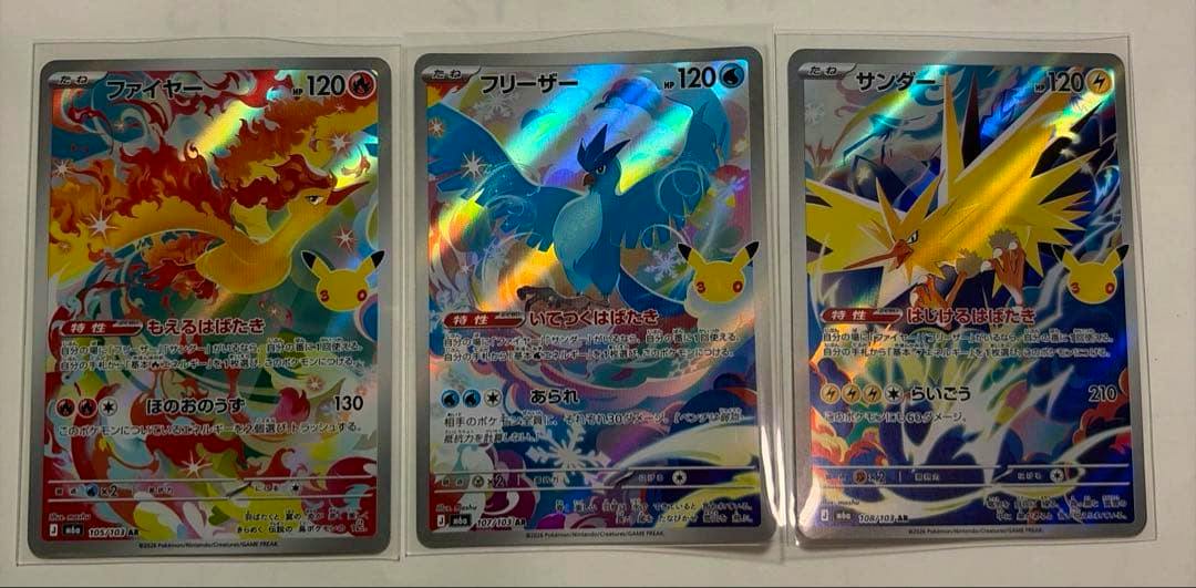 Three holographic Pokémon 30th AR art rare cards (ファイヤー, フリーザー, サンダー) in clear sleeves displayed side by side on a white surface.