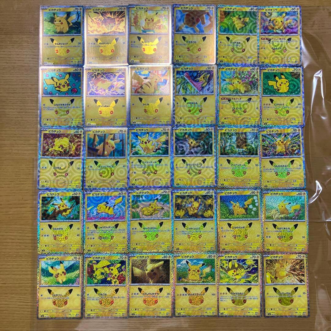 A grid of holographic Pikachu Pokémon trading cards from the 30th celebration set arranged on a wooden surface inside a clear plastic sleeve.