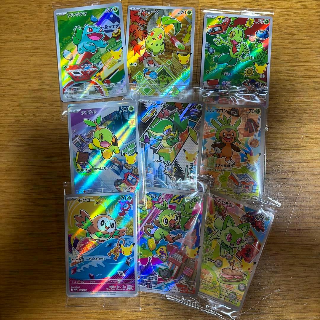 Several holographic Pokémon trading cards from the 30th Celebration set in plastic sleeves arranged on a wooden surface.