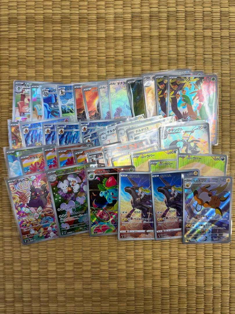 A spread of 40 Pokémon AR trading cards in protective sleeves laid out on a tatami mat.