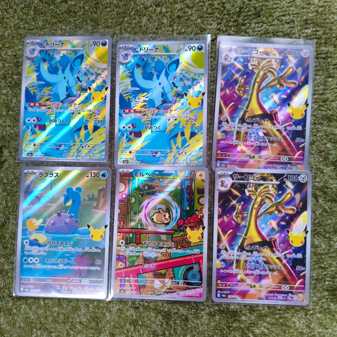 Six Pokémon trading cards in protective sleeves showing holographic front art arranged in two columns on a green surface.