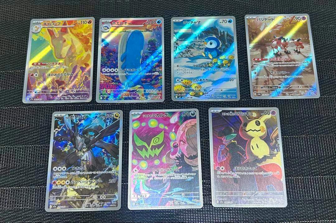 Eight Pokémon trading cards showing their front artwork arranged on a black textured surface.