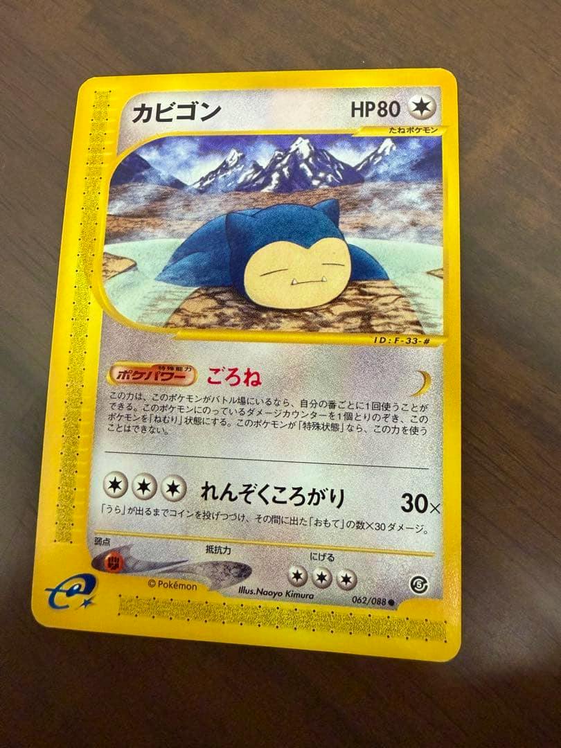 Photograph of the front of the Japanese Pokémon trading card ポケモンカードe カビゴン 062/088 showing the Snorlax artwork and card text on a wood surface.