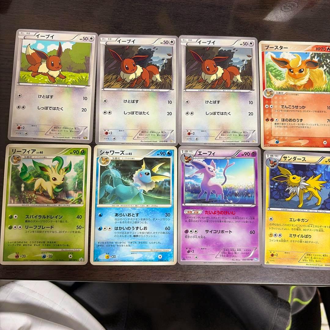 Eight Pokémon trading cards laid out on a table showing front artwork including Eevee and its evolutions.