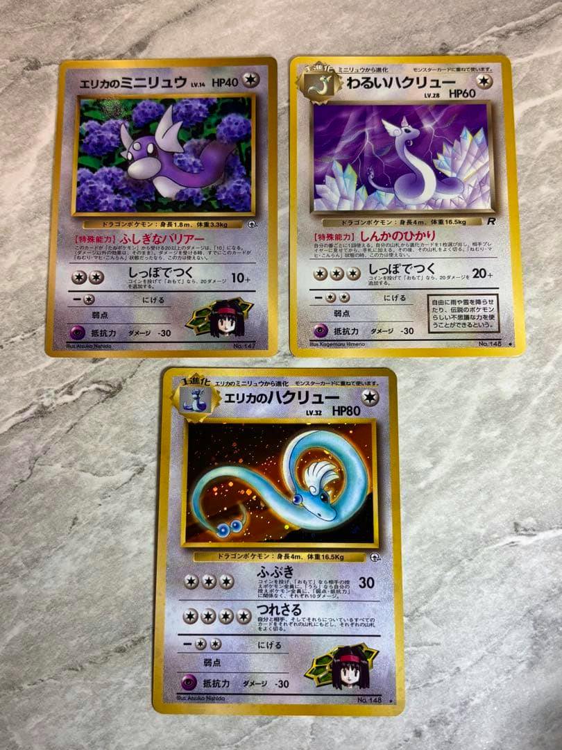 Fronts of three Japanese Pokémon trading cards including Erika's Hakuryu (Dragonair) holo card displayed on a stone surface.