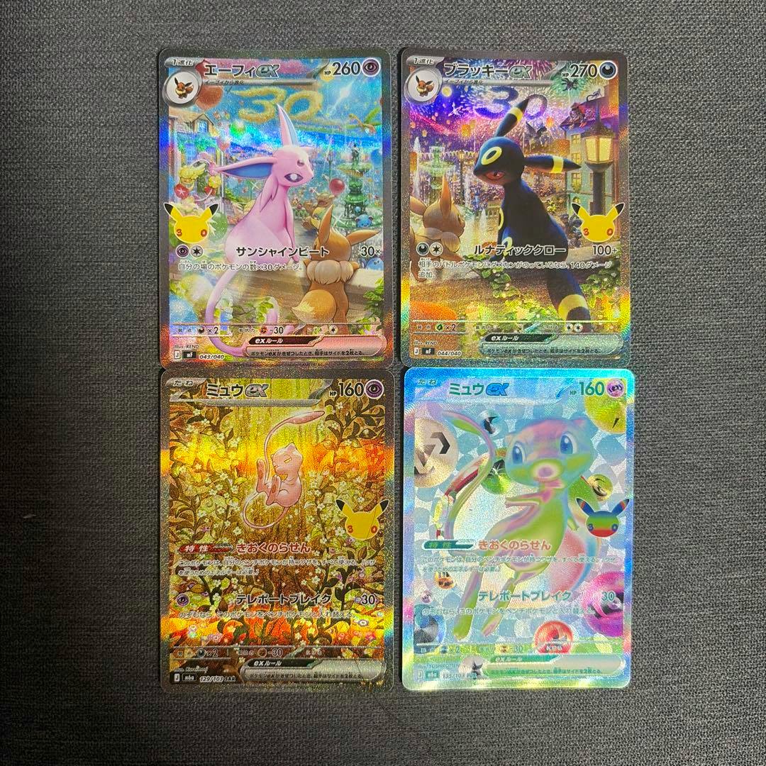 Four holographic Pokémon trading cards (エーフィex, ブラッキーex, ミュウex) arranged in a 2×2 grid on a dark textured surface.