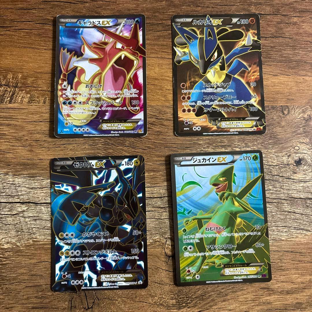 Four Pokémon EX trading cards showing the card fronts arranged on a wooden surface.