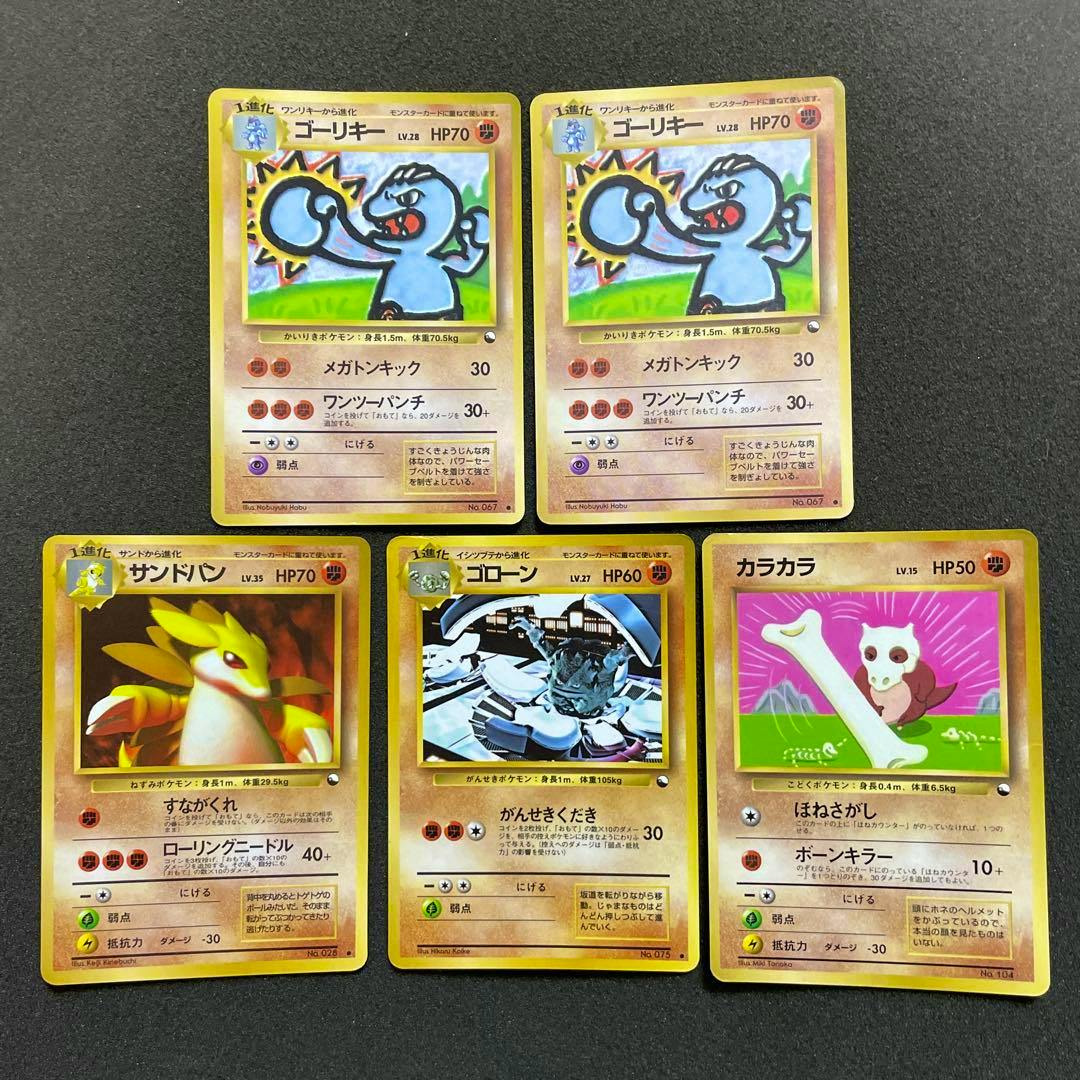 Five vintage Japanese Pokémon trading cards laid out on a dark surface, with two ゴーリキー cards at the top and three other Pokémon cards below.