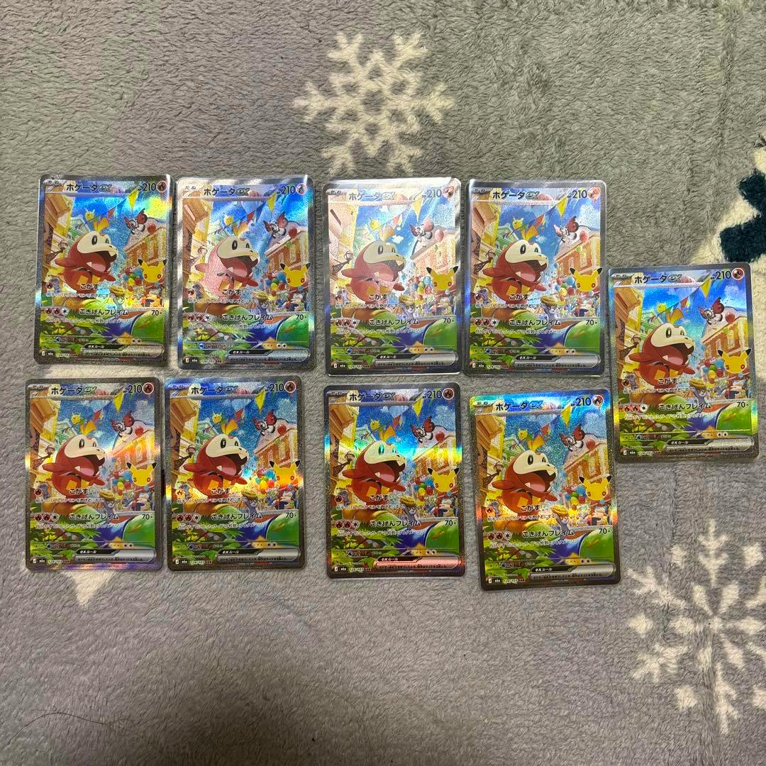 Nine holographic ホゲータex Pokémon trading cards arranged in rows on a gray patterned blanket.