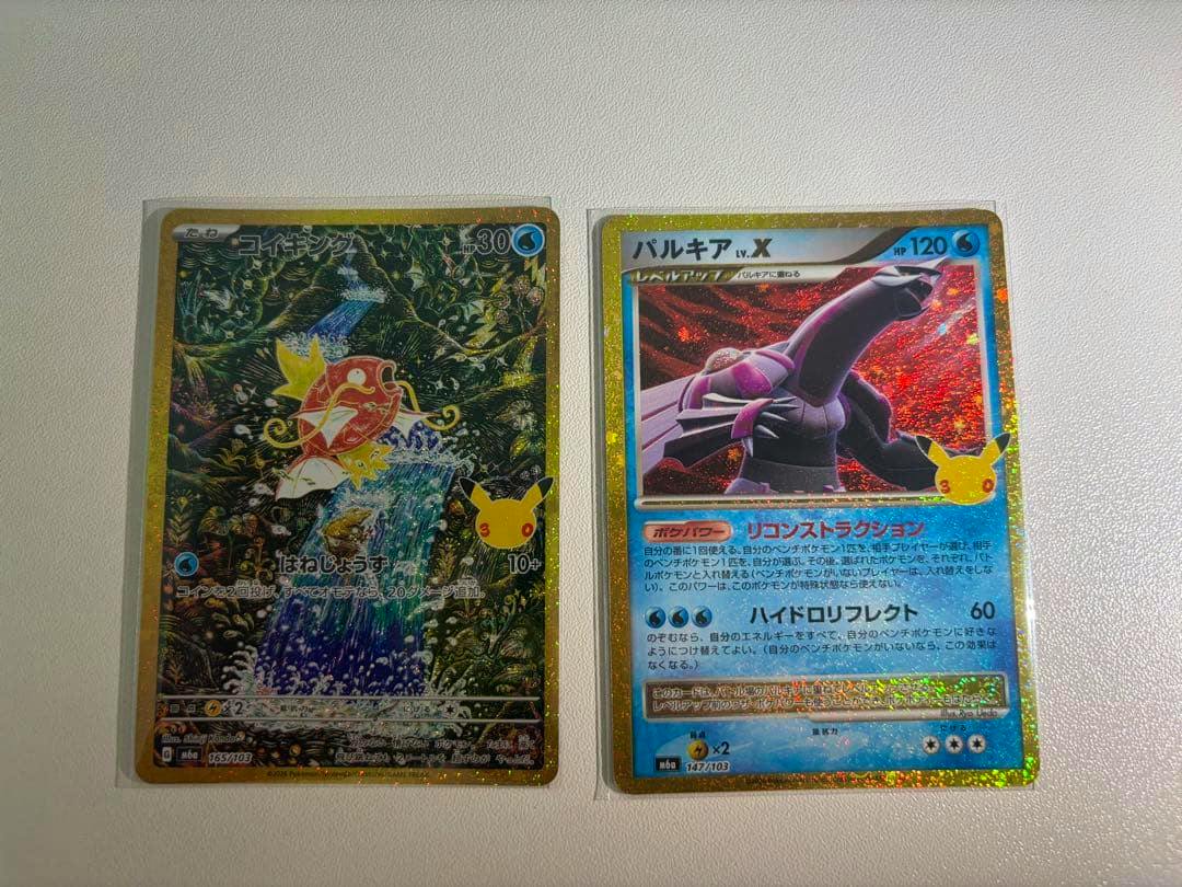 Main image shows two Pokémon trading cards side by side on a white surface: コイキングAR 165/103 (left) and パルキア 147/103 (right).