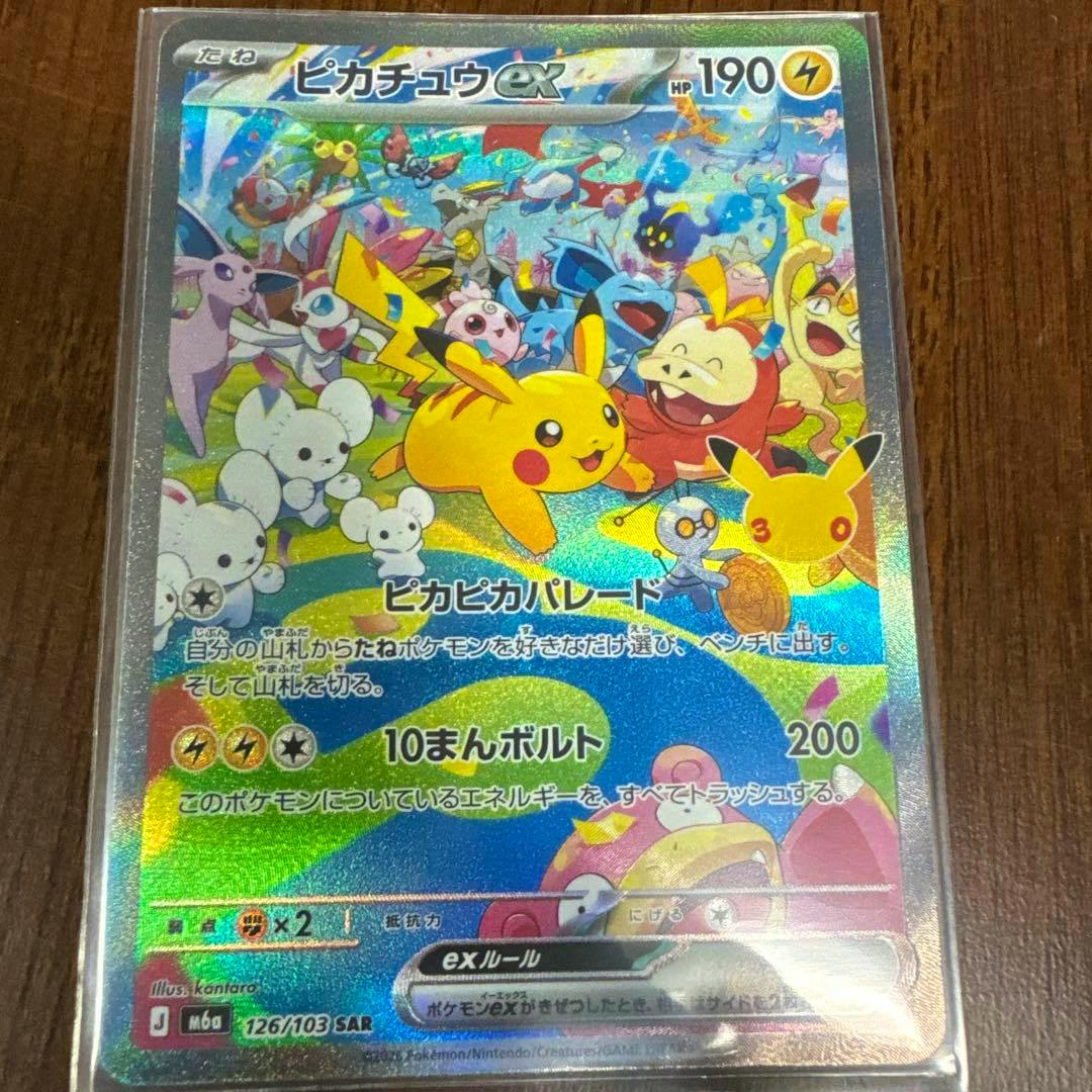 Holographic Pikachu ex trading card (126/103) photographed in a clear sleeve on a wooden surface.
