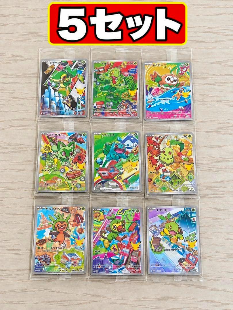 Nine Pokémon trading cards in protective sleeves arranged in a 3x3 grid on a light wood surface.
