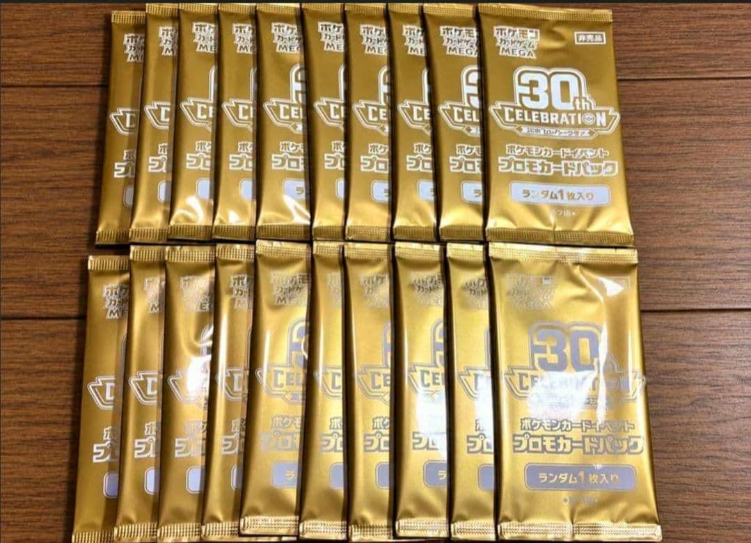 Twenty gold 30th CELEBRATION Pokémon promo card packs arranged on a wooden surface.