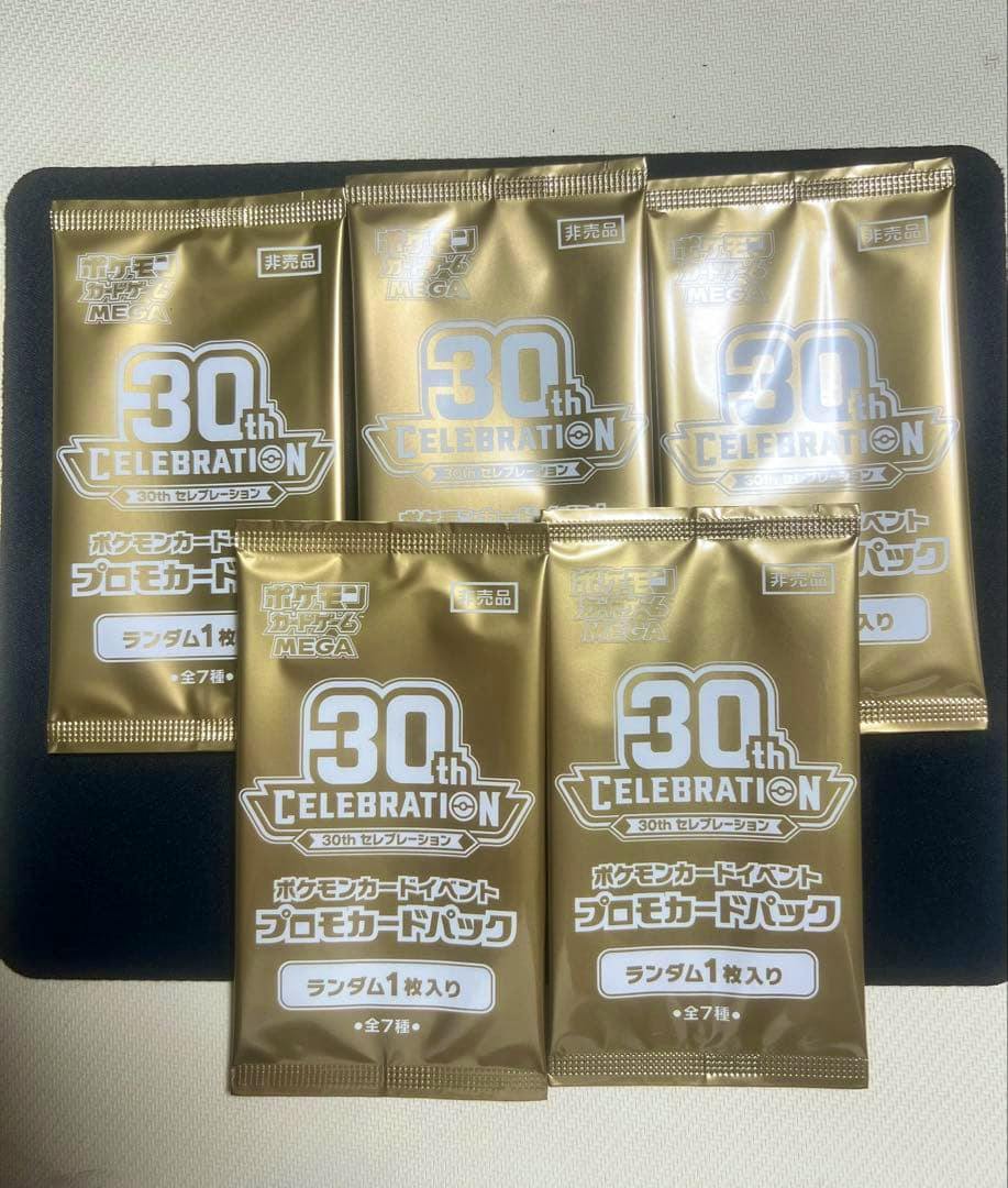 Five gold "30th Celebration" promo card packs arranged on a dark surface.