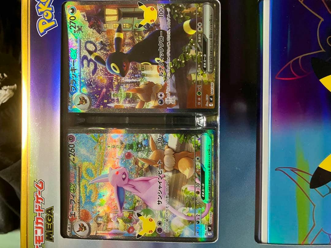 Two Pokémon 30th anniversary trading cards (Espeon ex and Umbreon ex) displayed in packaging.