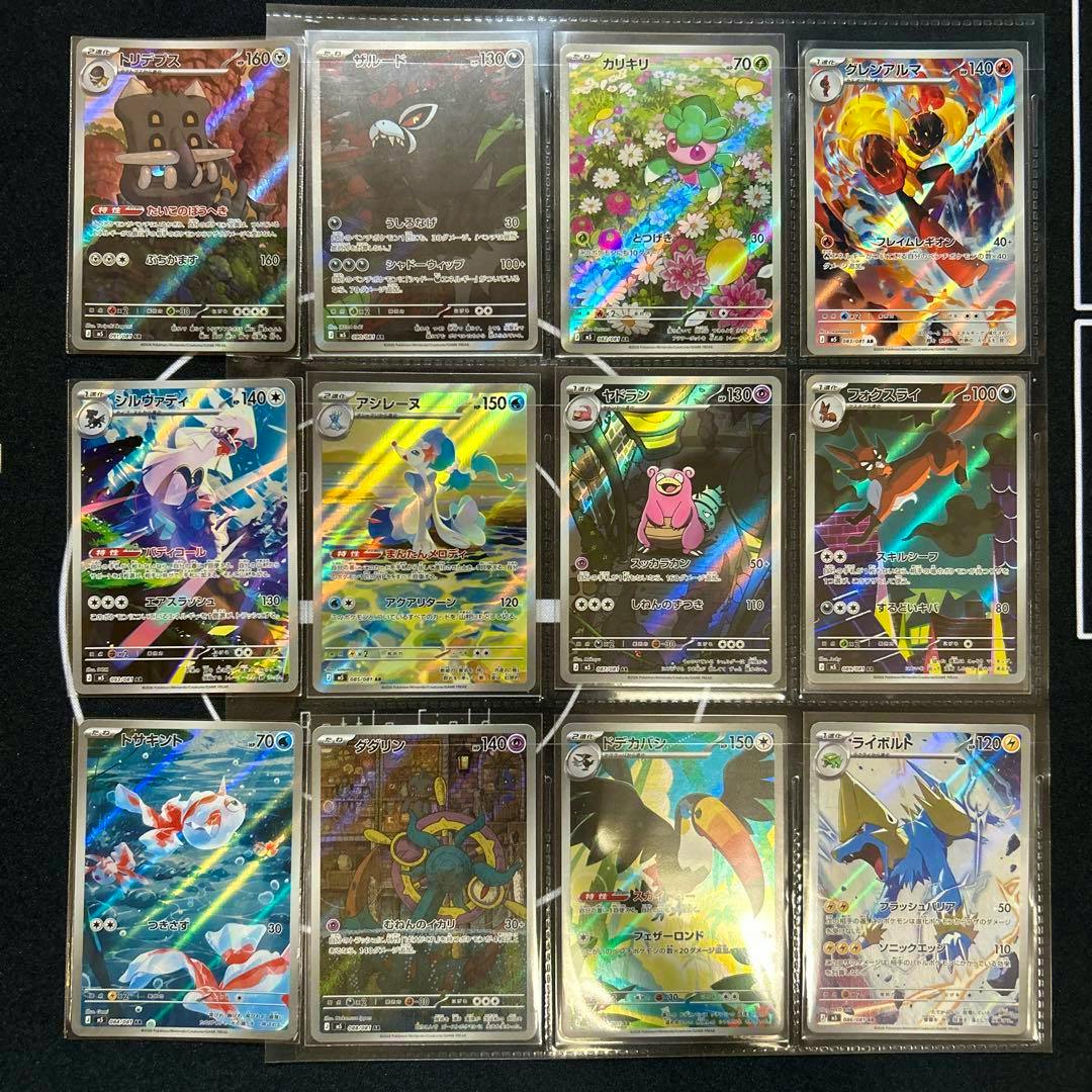 Photo of twelve Pokémon trading cards in plastic sleeves arranged in a 3x4 grid on a dark background.