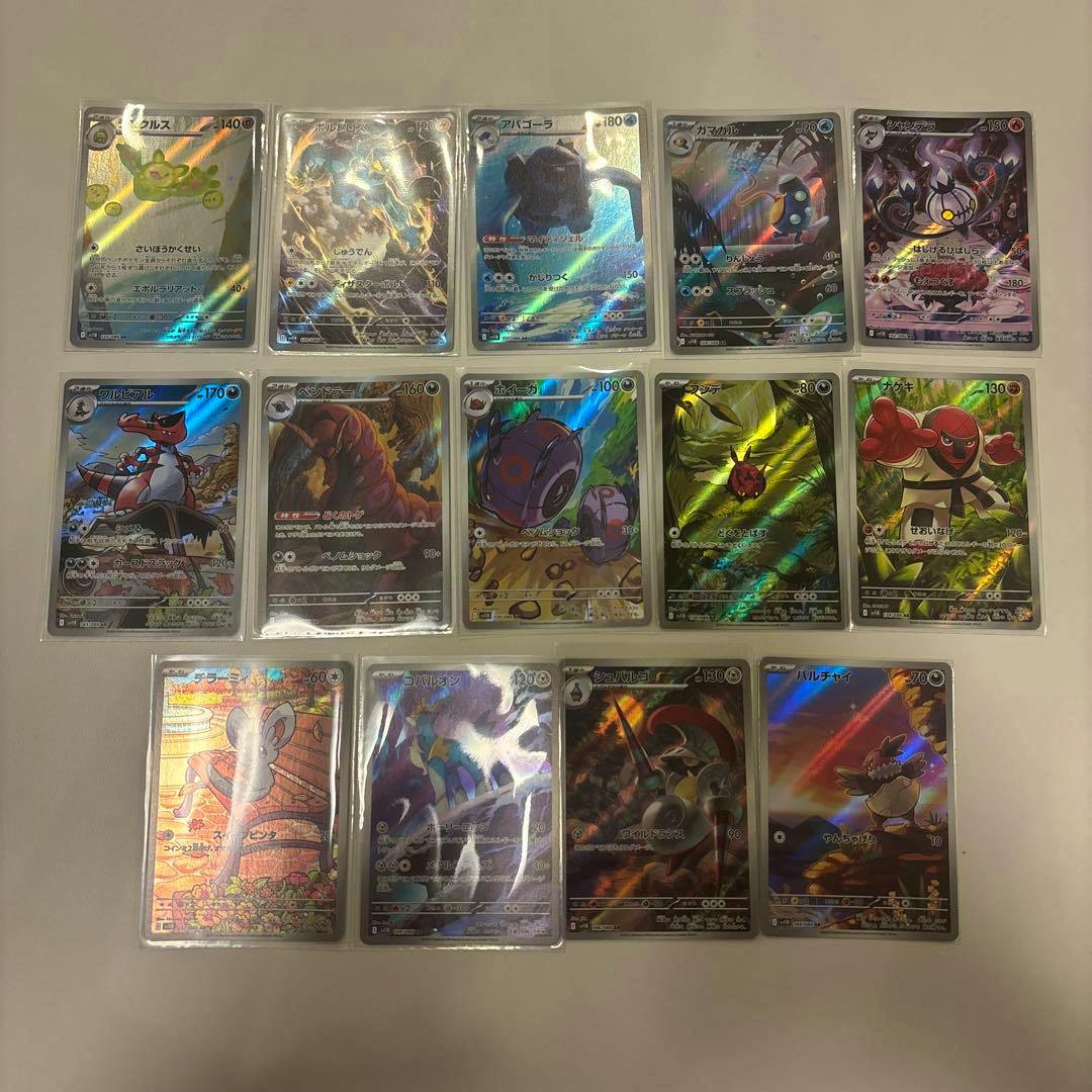 Photo of trading cards in protective sleeves arranged on a white surface.