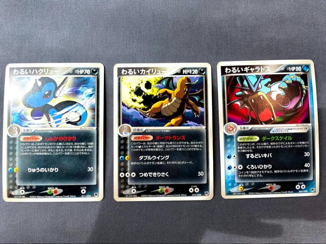 Three Japanese Pokémon trading cards — わるいハクリュー (Dark Dragonair), わるいカイリュー (Dark Dragonite), and わるいギャラドス (Dark Gyarados) — laid side by side on a gray background.