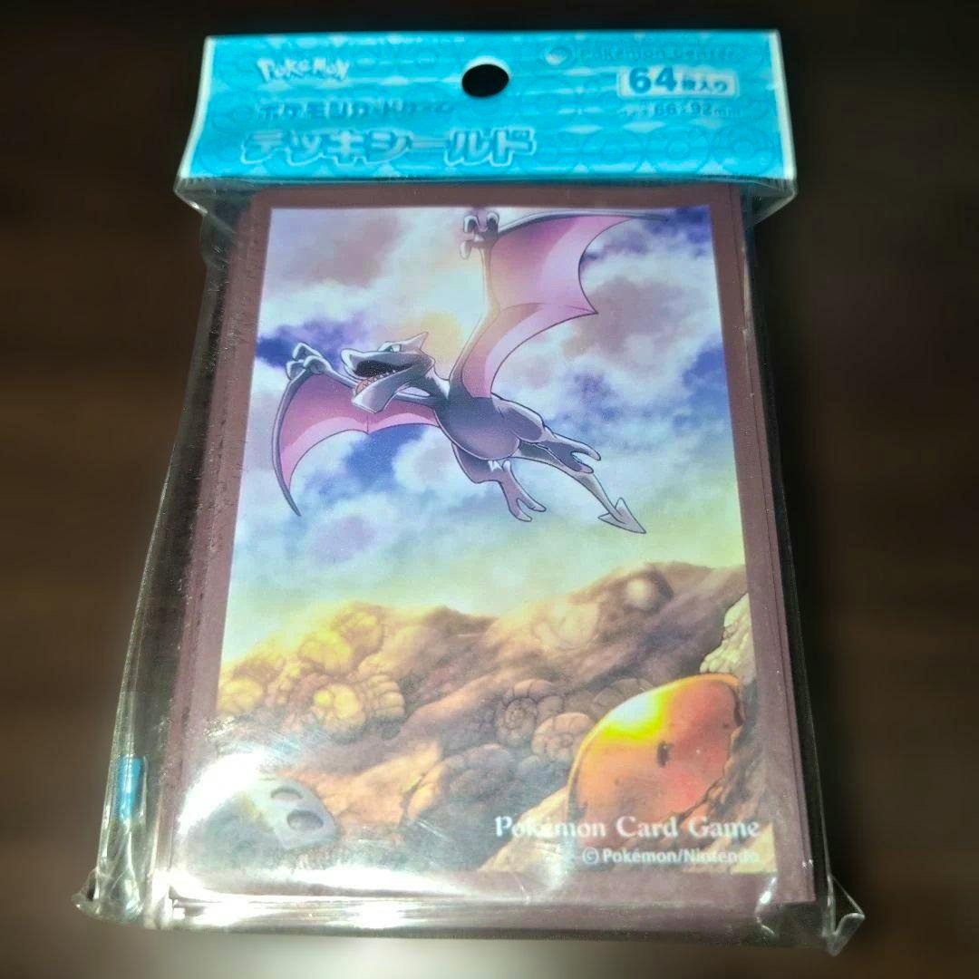 Packaged Pokémon card sleeves showing Ptera (Aerodactyl) artwork against a cloudy sky and rocky foreground.