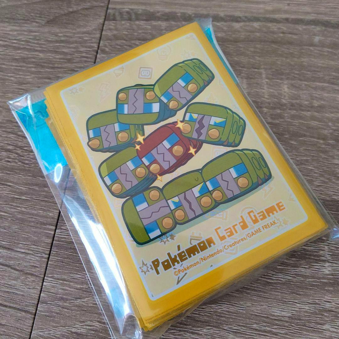 Sealed pack of Pokémon Card Game deck sleeves with yellow borders and a sparkling Dendimushi illustration, shown on a wooden surface.