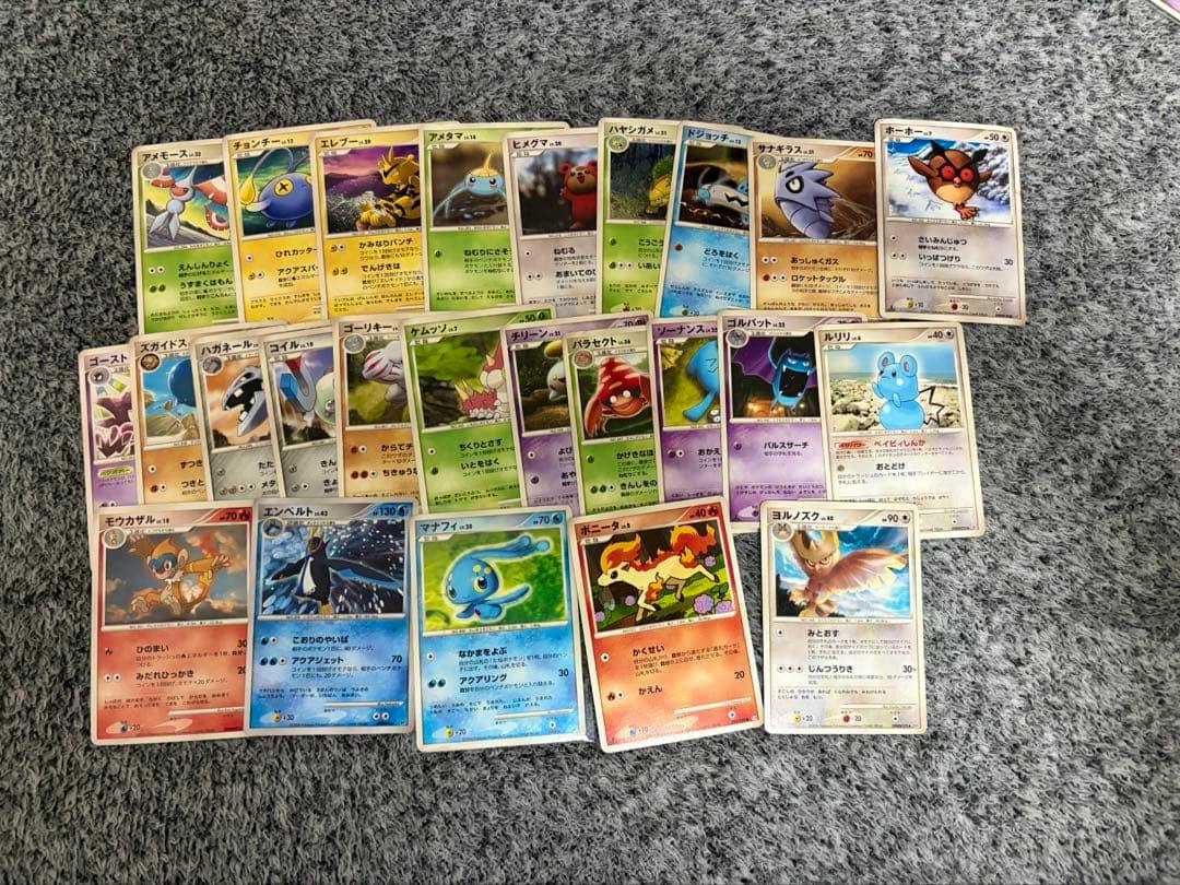 Photo of a laid-out 25-card Pokémon trading card set (DPBP) arranged on a gray carpet.