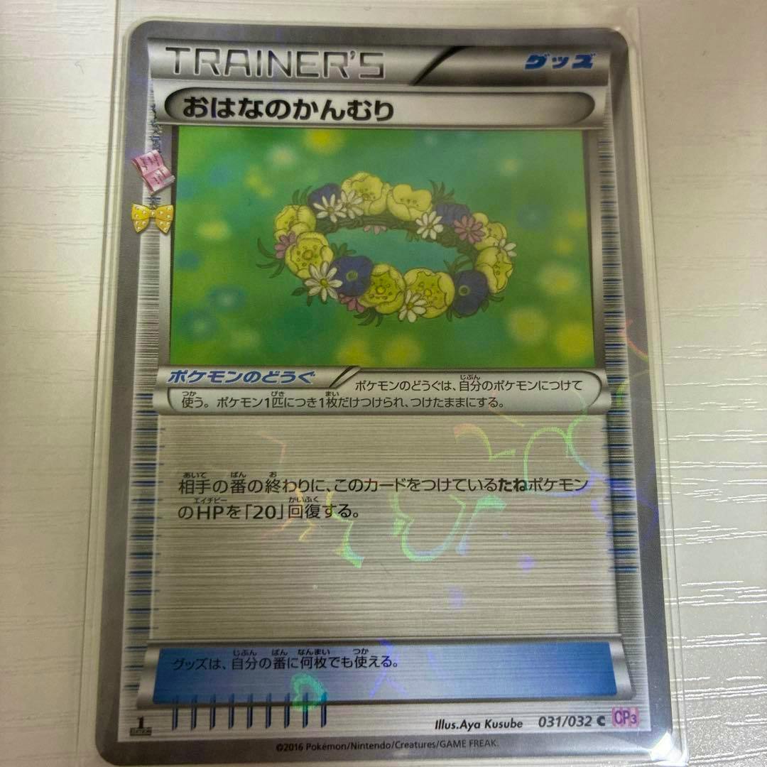 Front of the trading card showing a floral crown illustration and Japanese text, photographed in a protective sleeve.