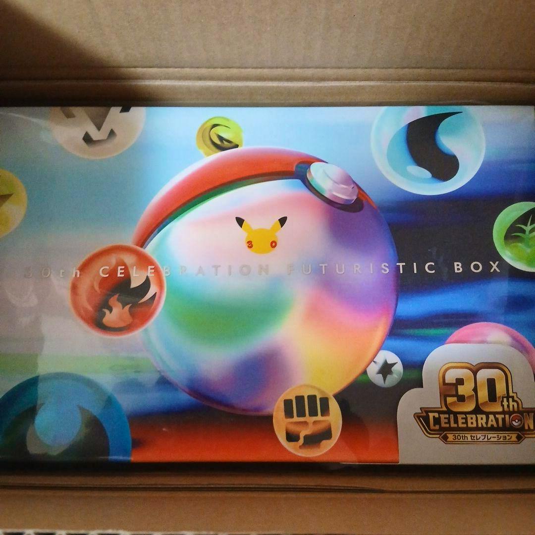 FUTURISTIC BOX packaging for Pokémon cards showing a colorful Poké Ball design and 30th Celebration logo inside a cardboard shipping box.