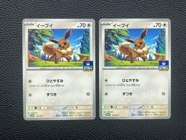 Two identical Eevee trading cards placed side-by-side on a black textured surface.