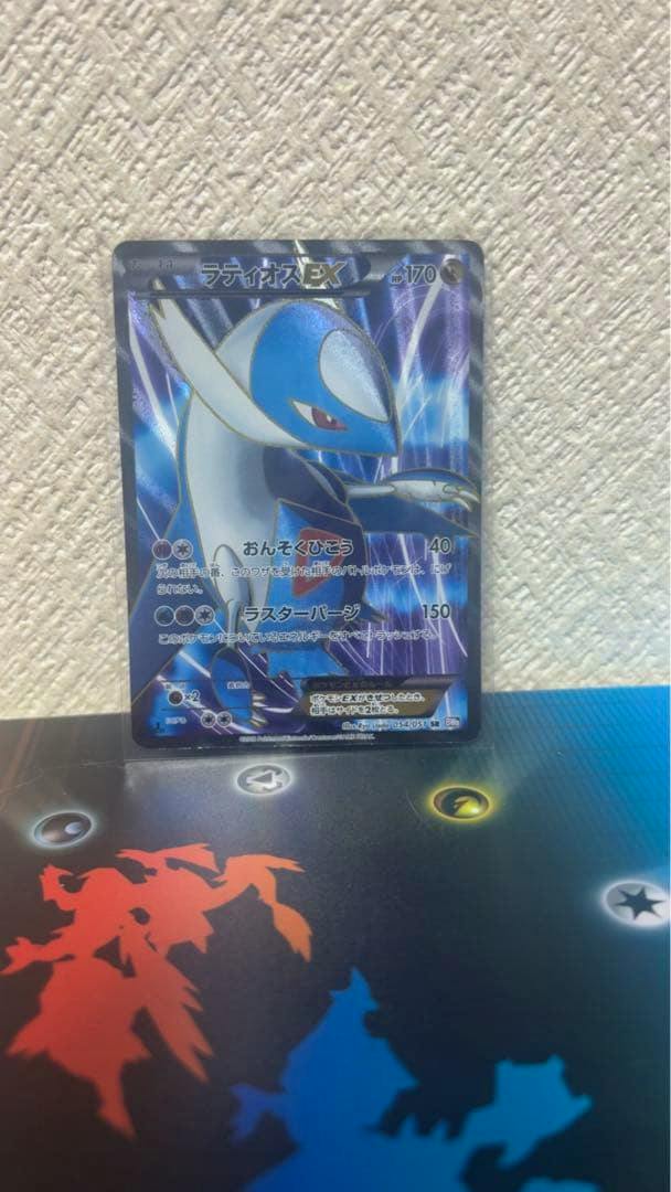 Front of the Pokémon trading card ラティオスEX shown upright in a sleeve on a playmat.