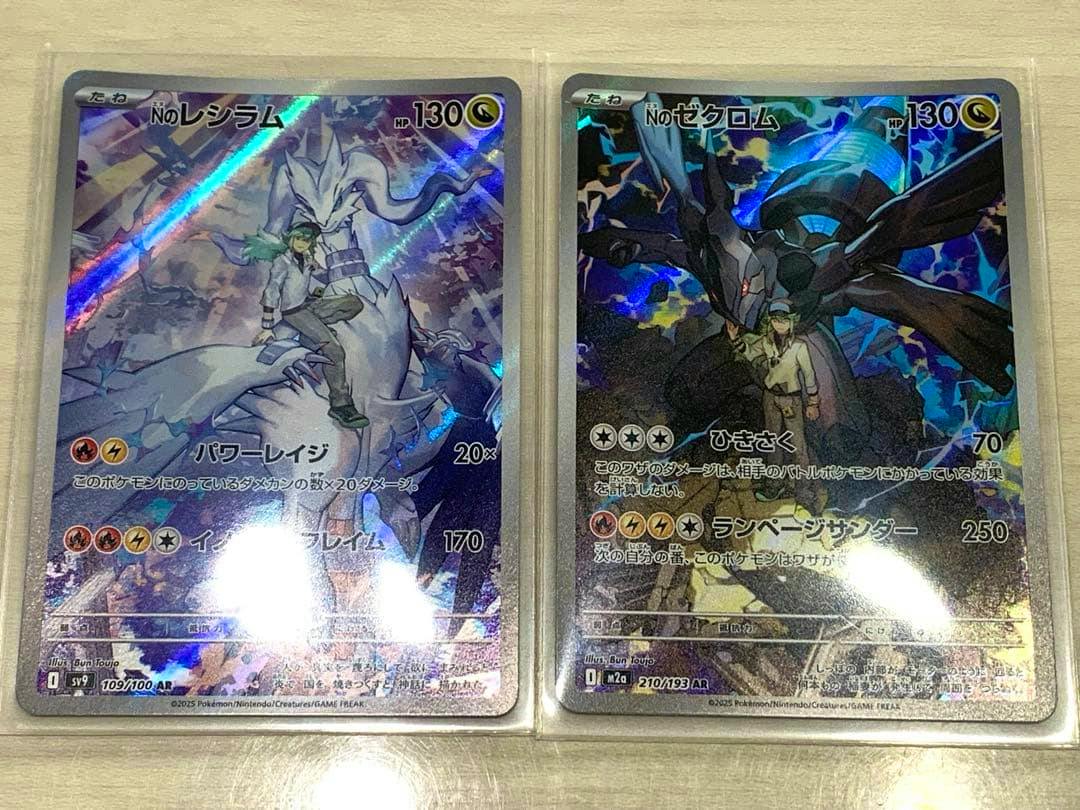 Two sleeved Pokémon trading cards (Nのゼクロム and Nのレシラム) shown face-up on a flat surface.