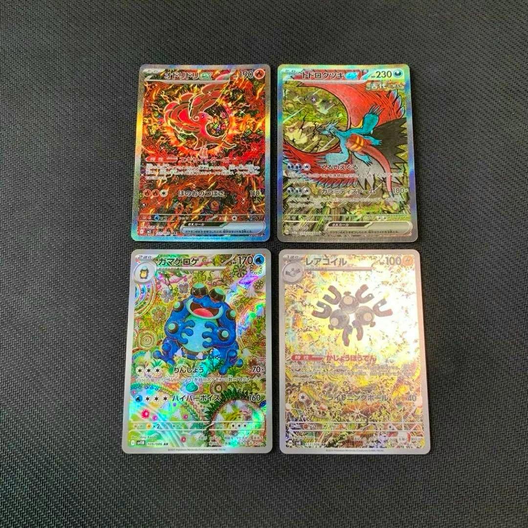 Four holographic Japanese Pokémon trading cards arranged two-by-two on a black textured background.
