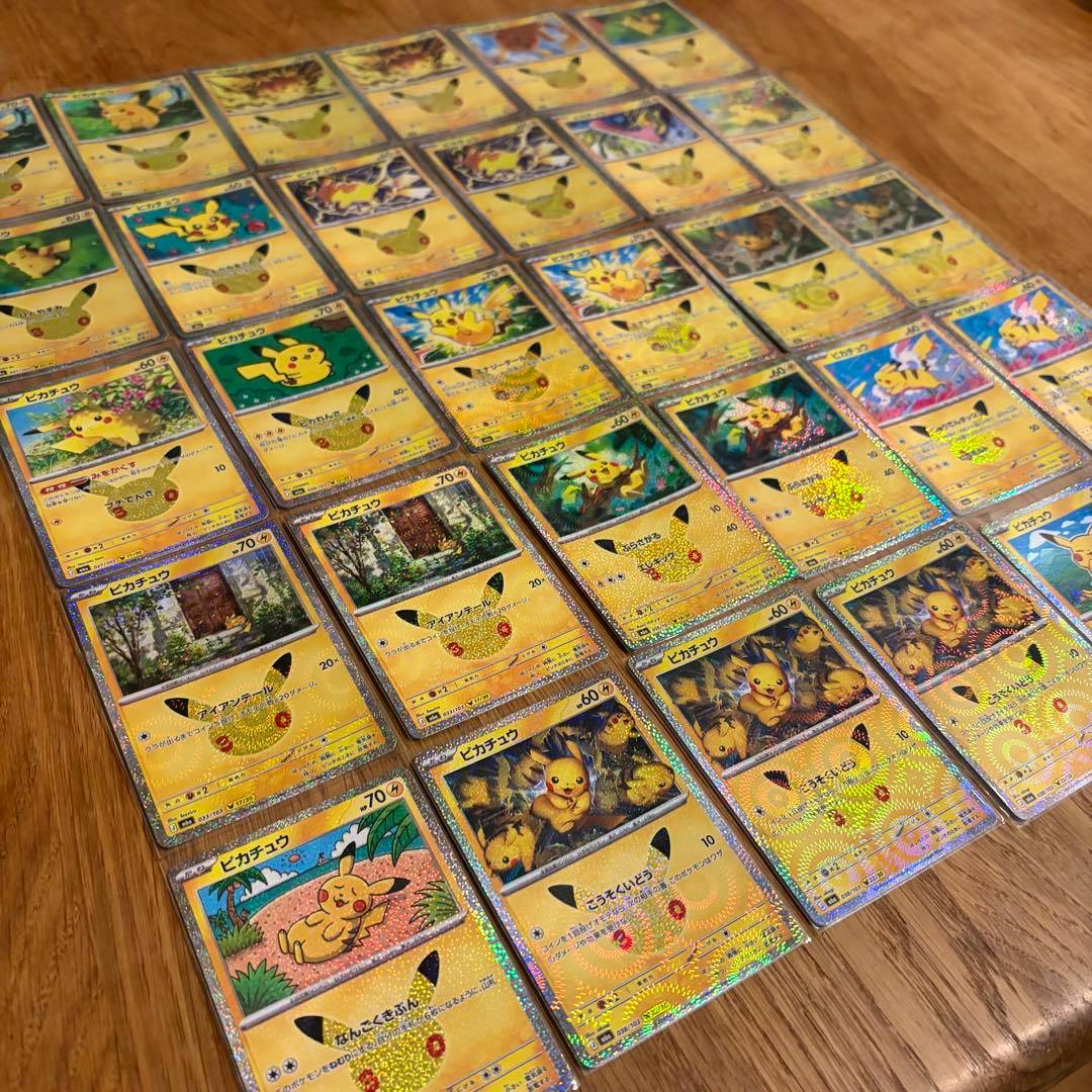 Angled photo of Pikachu trading cards from a bulk set arranged in rows on a wooden surface.