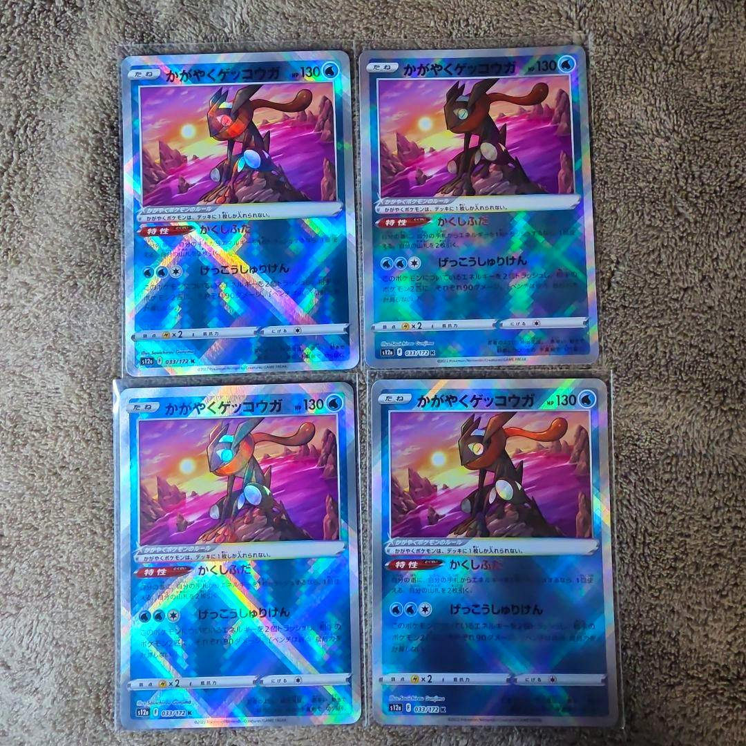Four holographic Pokémon trading cards (かがやくゲッコウガ) arranged in a 2x2 grid on a carpeted surface.