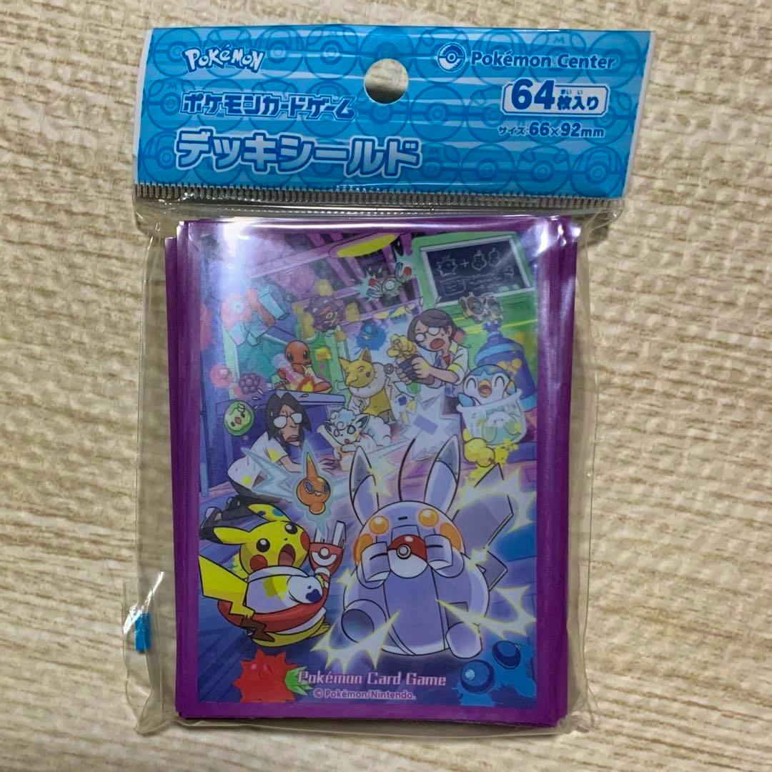 Unopened pack of Pokémon 'Deck Shield' card sleeves with purple borders and colorful laboratory-themed artwork visible through original plastic packaging.