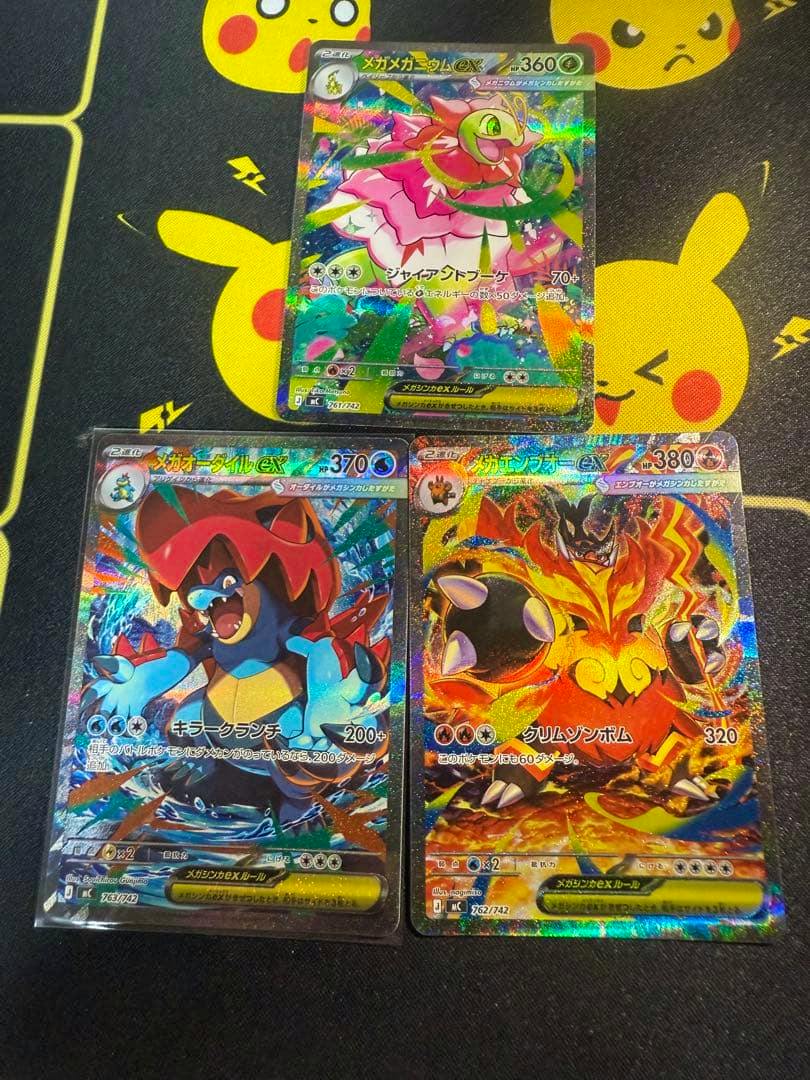 Three holographic Pokémon trading cards from the Start Deck, showing a Mega Meganium ex card at the top and two Mega ex cards below.