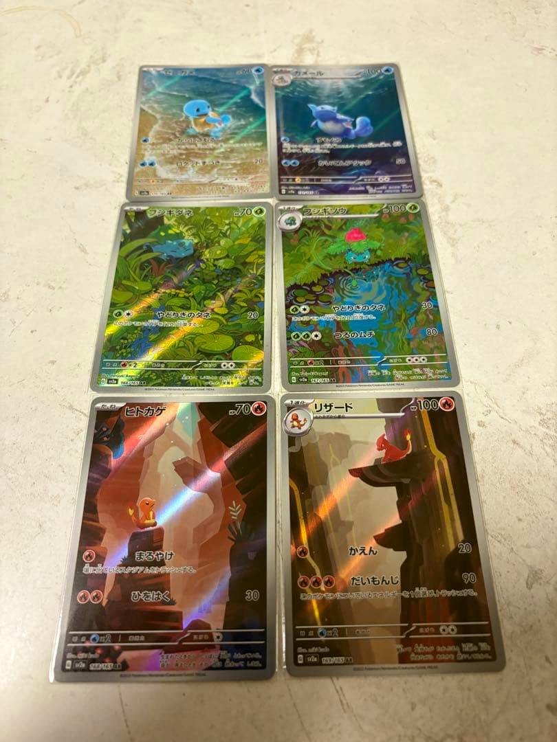 Six Pokémon trading cards from a starter trio AR set arranged on a light tabletop.