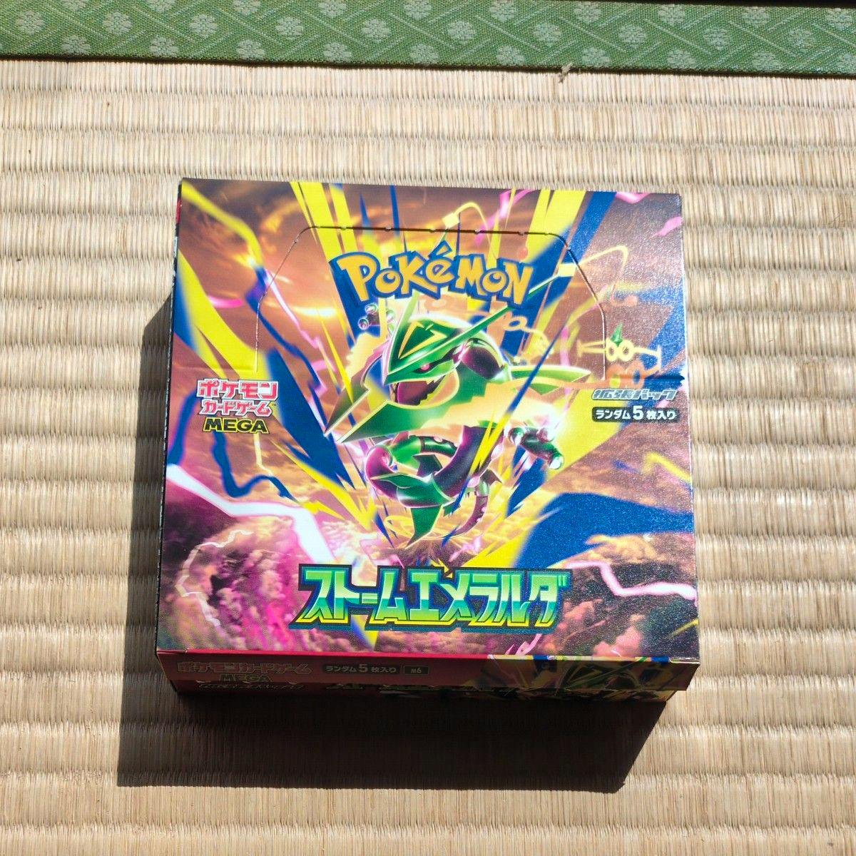 A Japanese Pokémon Card Game "ストームエメラルダ" booster box photographed on a tatami mat.