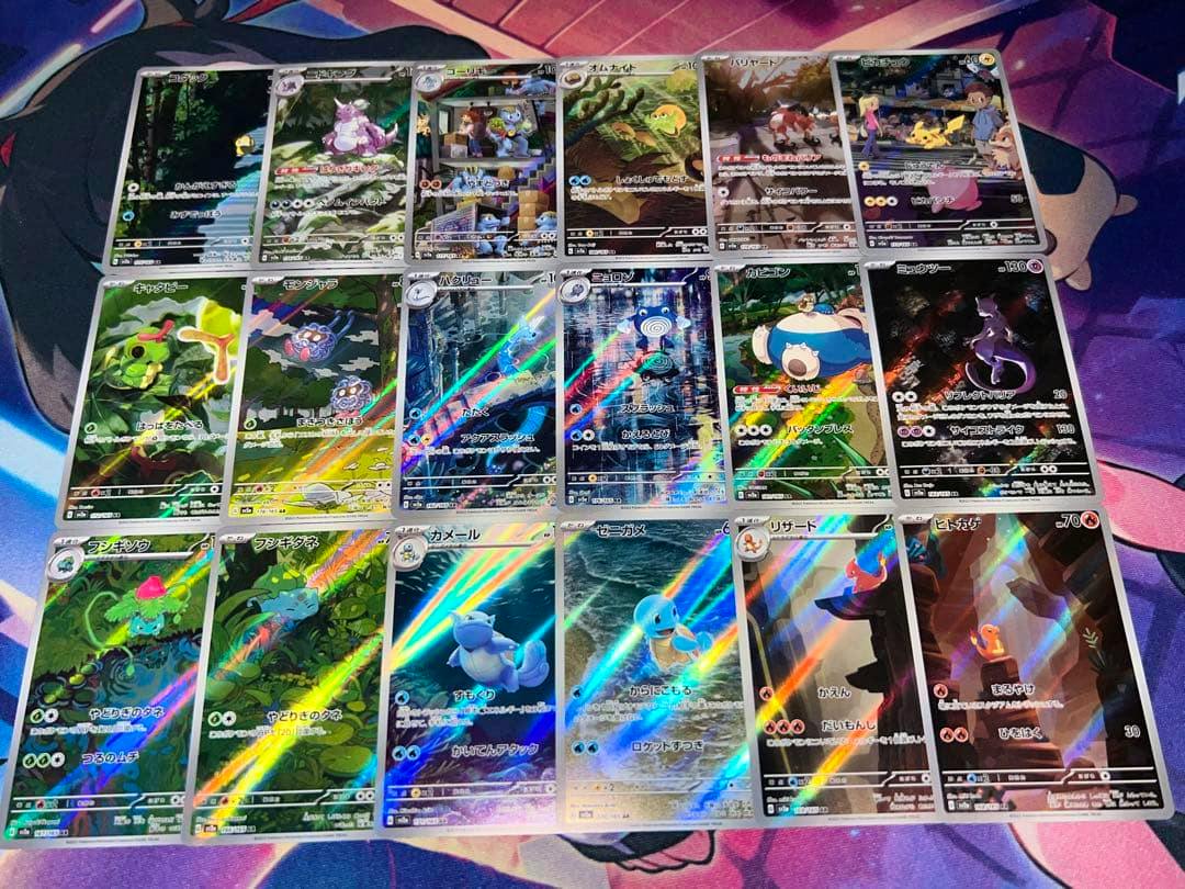 Eighteen holographic Pokémon trading cards laid out in a grid on a playmat.
