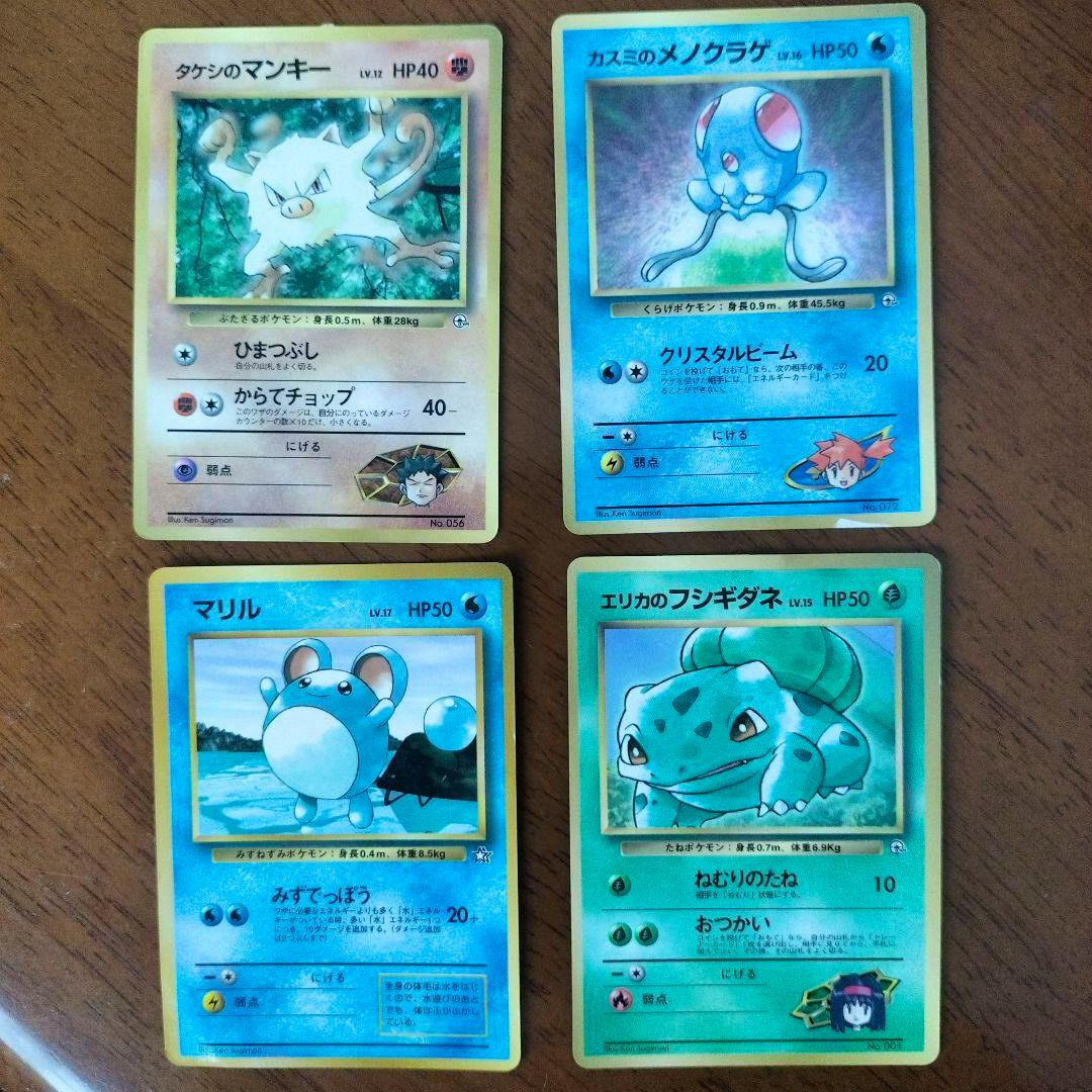 Four Japanese Pokémon trading cards (old-back era) showing the cards' fronts laid out on a wooden surface.