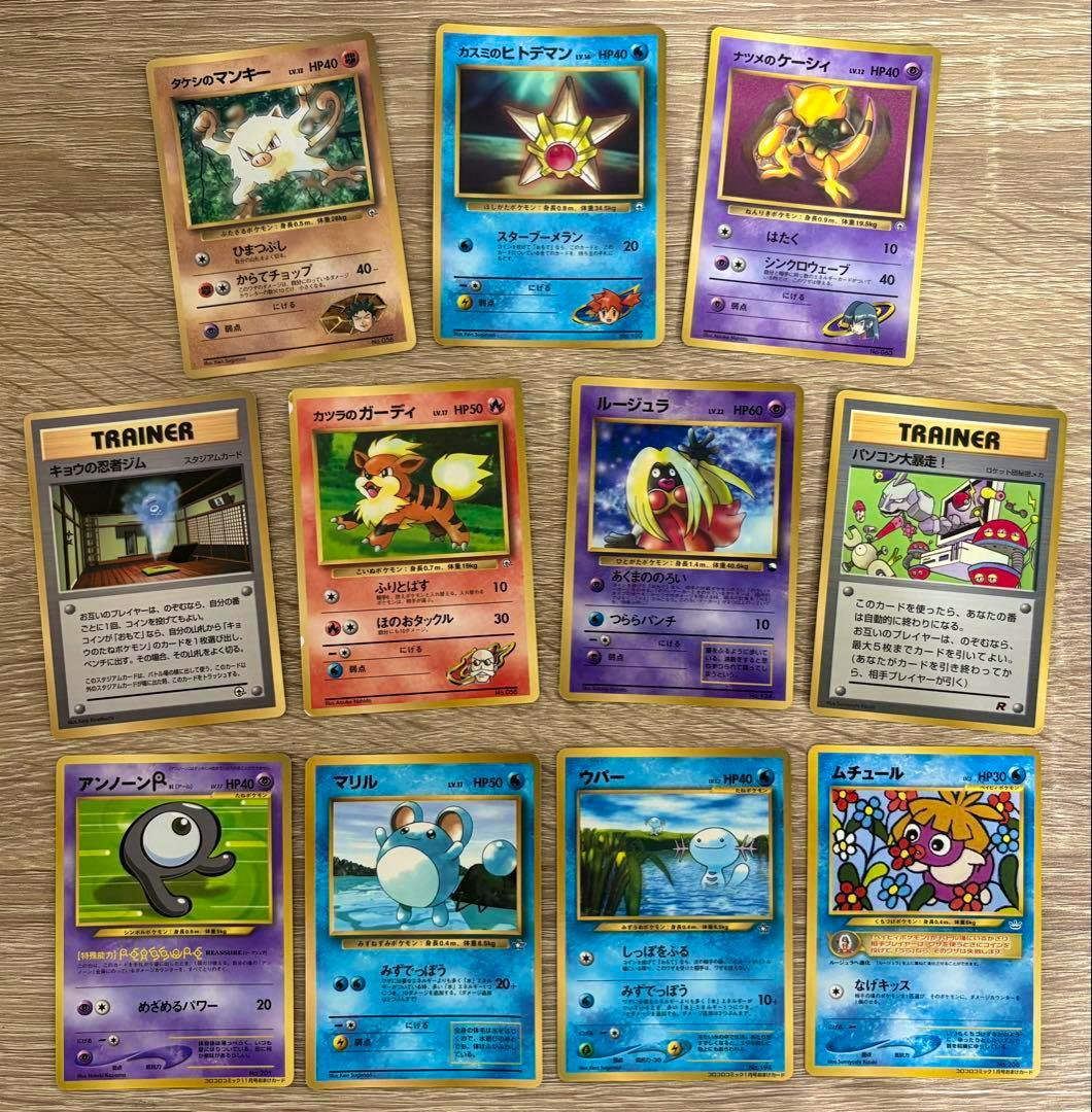 A spread of Japanese Pokémon trading cards showing the fronts (old-style cards) laid out on a wooden surface.