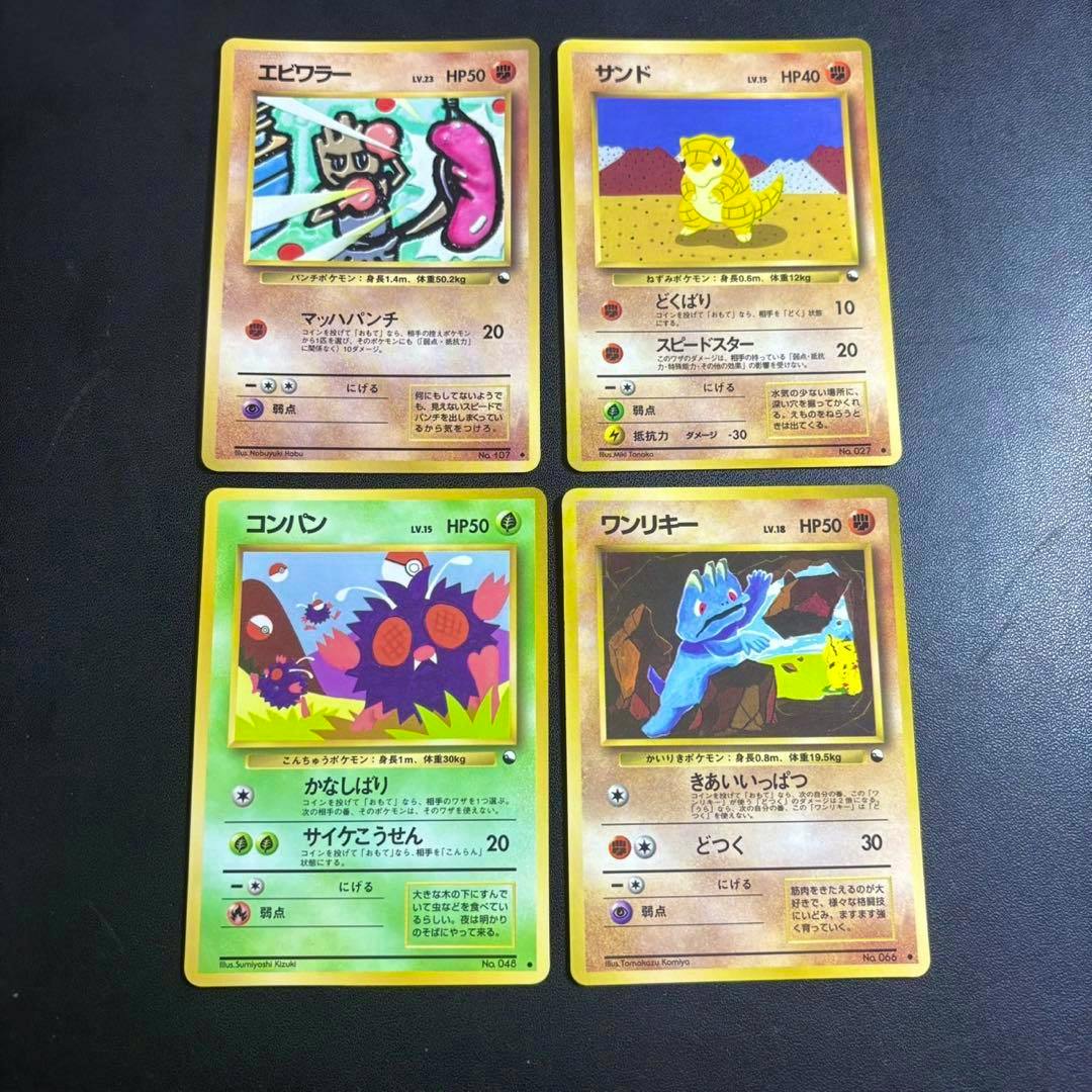 Four Japanese Pokémon trading cards laid out in a two-by-two grid on a black surface.