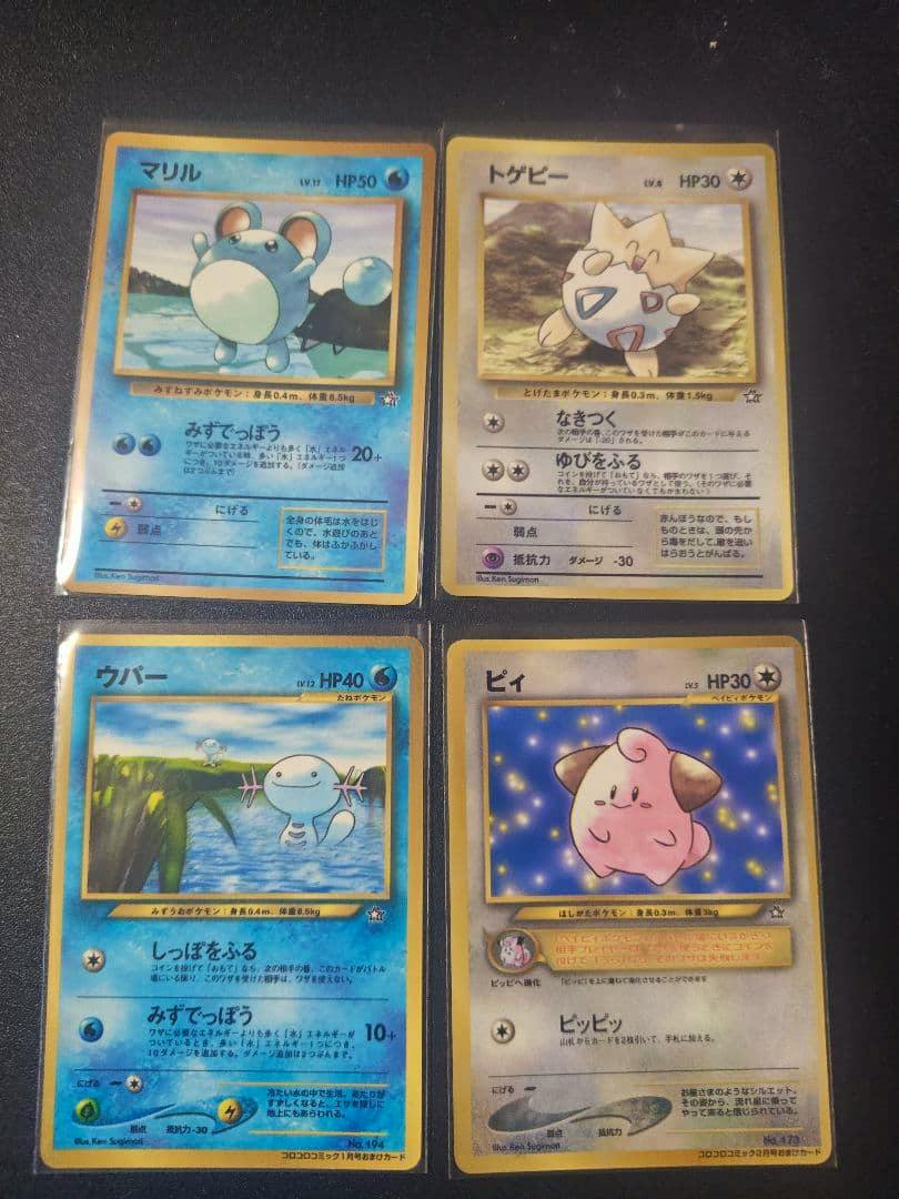 Four Pokémon trading cards in protective sleeves laid out on a dark surface, showing Marill, Togepi, Wooper, and Cleffa.