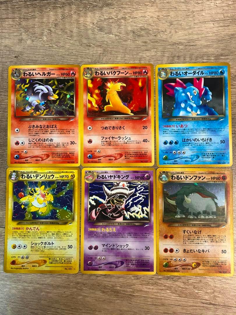 Six Japanese わるいシリーズ Pokémon trading card fronts arranged in two rows on a wooden surface.