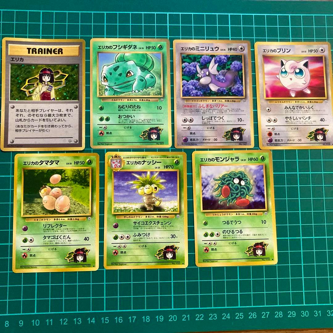 Several Erika Pokémon trading cards (old-back) laid out on a green gridded cutting mat.