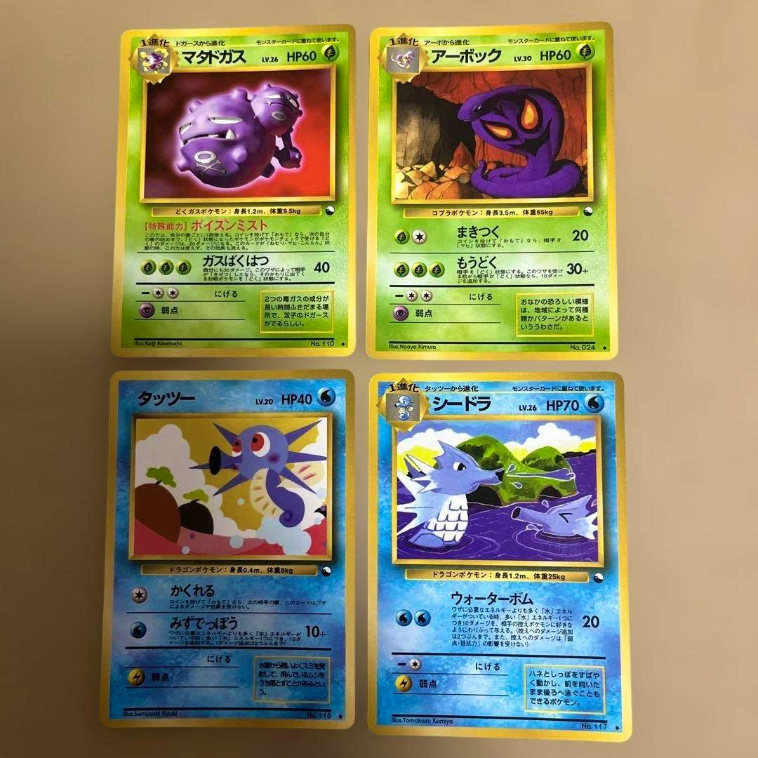 Four Japanese Pokémon trading cards laid out in two rows—two green cards above and two blue cards below—on a beige background.
