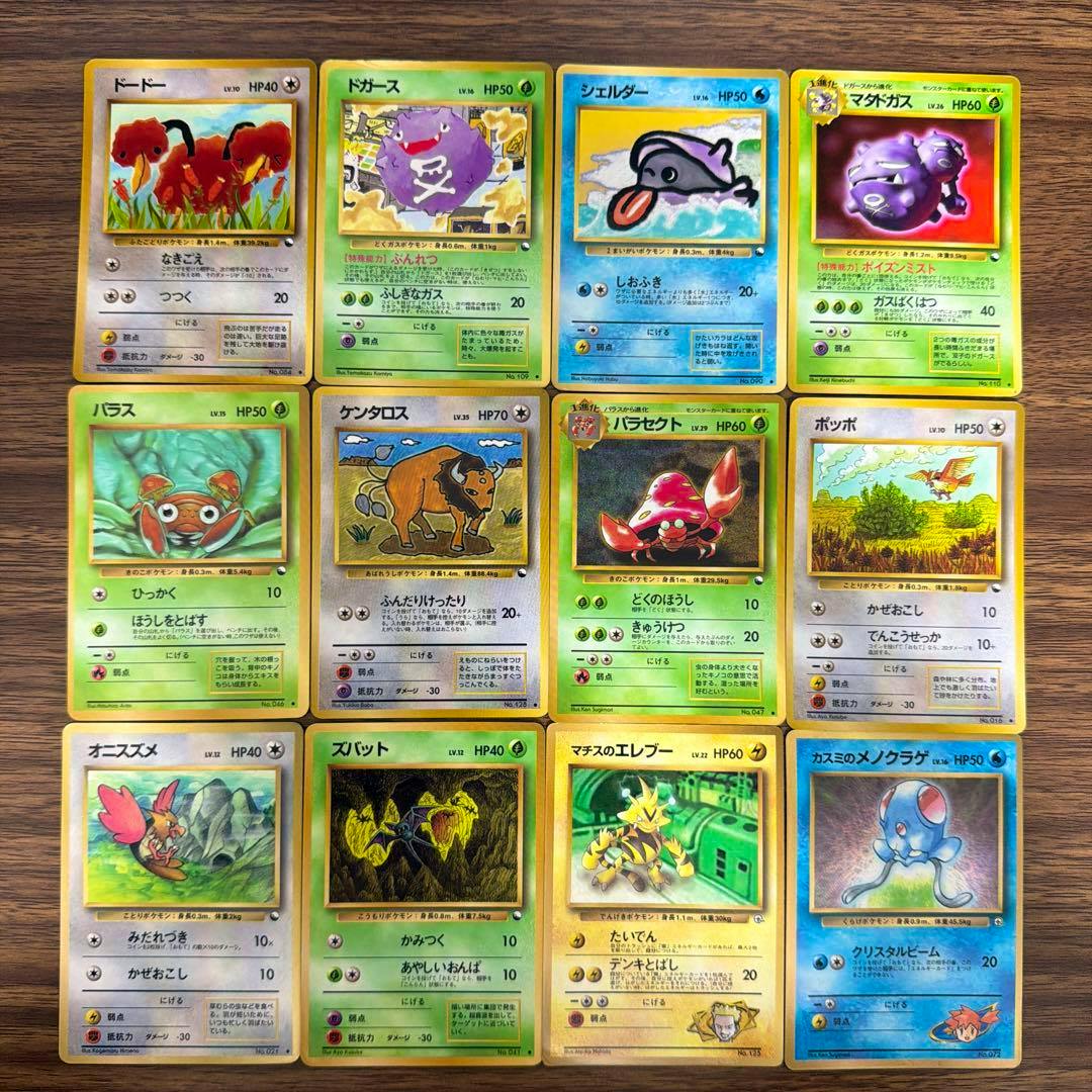 Twelve Japanese Pokémon trading cards arranged in a 3x4 grid on a wooden surface, showing the card fronts.