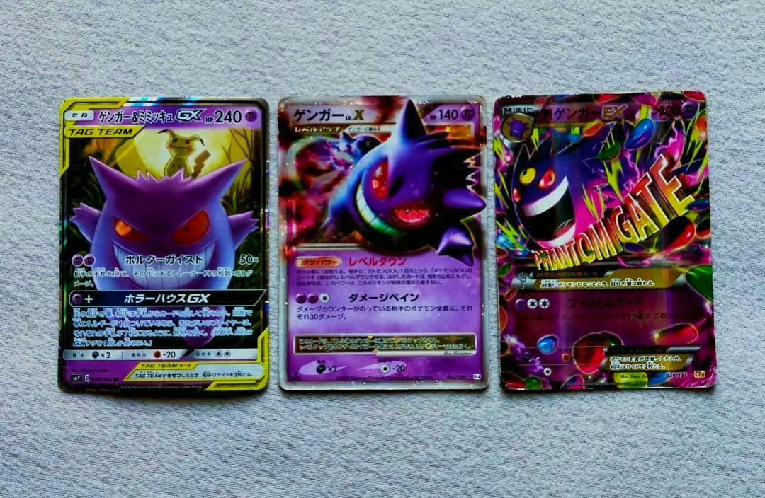 Three Pokémon trading cards laid side-by-side on a light textured surface: Gengar & Mimikyu GX at left, Gengar LV.X in the center, and M Gengar ex at right.