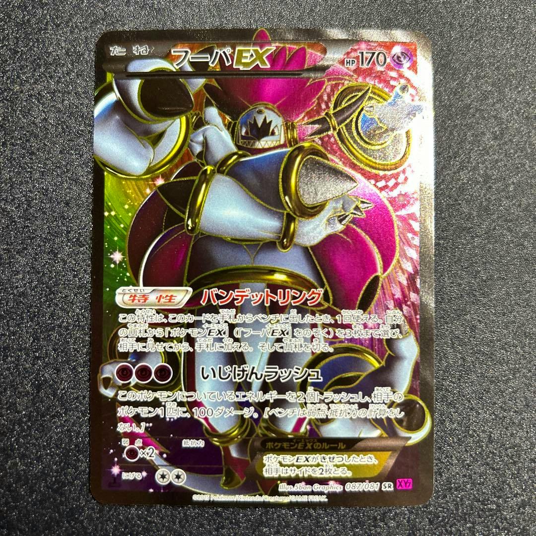 Photograph of the front of a Japanese フーパEX (Hoopa EX) Pokémon trading card placed on a dark textured surface.